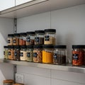 Jars filled with various spices and seeds are neatly arranged on a stainless steel Royalty Free Stock Photo