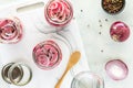 Jars of freshly made pickled red onions with peppercorns and vinegar.