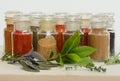 Jars of herbs and spices on a marble slab with fresh herbs