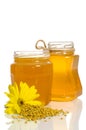 The jars of honey near a pile of pollen and flower