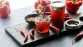 Jars of hot pepper jelly on a board surrounded by chili peppers and red peppers. Royalty Free Stock Photo