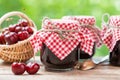 Jars of jam and basket with cherry.