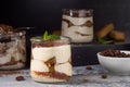 Jars with layered tiramisu cake on dark rustic background