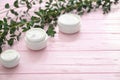 Jars Of Moisturizing Cream With Herbal Extract On Wooden Table
