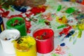 Jars with multi-colored finger paints on the background of children`s prints and blots of paint