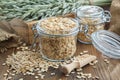 Jars of oat flakes, green oat ears and sack on wooden table