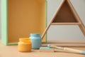 Jars of paints and brush on wooden table. Interior element