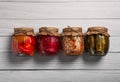 Jars with pickled vegetables on white wooden table, flat lay Royalty Free Stock Photo