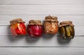 Jars with pickled vegetables on white wooden table, flat lay Royalty Free Stock Photo