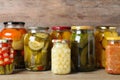 Jars with pickled vegetables on wooden table against background Royalty Free Stock Photo