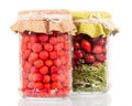 Jars with rowan berries and rose hips on white. Royalty Free Stock Photo