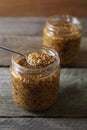 Jars and spoon of whole grain mustard on wooden table, closeup Royalty Free Stock Photo