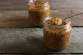 Jars and spoon of whole grain mustard on wooden table, closeup. Space for text Royalty Free Stock Photo