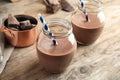 Jars with tasty chocolate milk on wooden table.