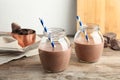 Jars with tasty chocolate milk on wooden table. Royalty Free Stock Photo