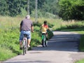 Jaslo, Poland - 9 july 2018:The father and daughter ride bicycles along the asphalt road amid the summer greens in the rays of the