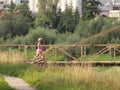 Jaslo, Poland - 9 july 2018:Scandinavian / nordic walking. A woman in city clothes stroll through the summer`s grass in the rays o