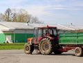 Jaslo/Yaslo, Poland - april 14, 2018: Two farmers near the tractor with a trailer in the parking lot near the hangar. Agricultural