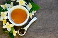 Jasmine dry green tea leaves in a spoon with jasmine flowers and cup of tea on old wooden background.Healthy drink,diet or herbal Royalty Free Stock Photo