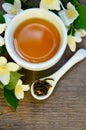 Jasmine dry green tea leaves in a spoon with jasmine flowers and cup of tea on old wooden background. Royalty Free Stock Photo