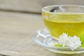 Jasmine flowers with cup tea on wooden background