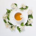 Jasmine leaves and flowers around cup of green tea on white background. Top view and concept. Royalty Free Stock Photo