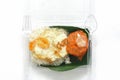 Jasmine rice with a pork curry and fried egg in a transparent plastic box package with banana leaf at a bottom Royalty Free Stock Photo