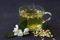 Jasmine tea. Cup of hot herbal tea with jasmine fresh flowers on a black table. Royalty Free Stock Photo