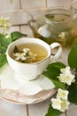 Jasmine tea with jasmine flowers on white wooden table background. Cup of hot green tea with jasmine flavor, fresh jasmine flowers Royalty Free Stock Photo