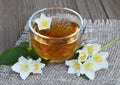 Jasmine tea in a glass cup and fresh flowers on old wooden table.Healthy drink,diet or herbal medicine concept. Royalty Free Stock Photo
