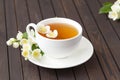 Jasmine tea with jasmine flowers on wooden table background. Cup of hot green tea with jasmine flavor, fresh jasmine flowers. Royalty Free Stock Photo