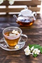 Jasmine tea in transparent cup, jasmine flowers and teapot on wooden table. Copy space. Tea party Royalty Free Stock Photo