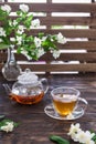 Jasmine tea in transparent cup, jasmine flowers and teapot on wooden table. Copy space. Tea party Royalty Free Stock Photo