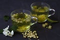 Jasmine tea. two cups of hot herbal tea with linden flowers on a black table Royalty Free Stock Photo