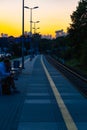 Beautiful cloudy sunset over long train platform with few people at waiting for train to come