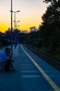 Beautiful cloudy sunset over long train platform with few people at waiting for train to come