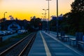 Beautiful cloudy sunset over long train platform with few people at waiting for train to come