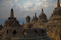 Amazing sunrise view of meditating Buddha statue and stone stupas. Ancient Borobudur Buddhist temple Royalty Free Stock Photo