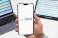 Java logo on the screen of smartphone in mans hand on the workplace background Royalty Free Stock Photo