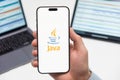 Java logo on the screen of smartphone in mans hand on the workplace background Royalty Free Stock Photo
