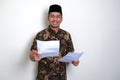 Javanese man smiling friendly while giving a document paper