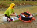 Indonesian woman washes clothes in unsanitary water canal