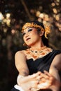 Javanese woman with golden crown and black costume chilling inside the forest while wearing makeup