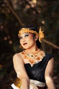 Javanese woman with golden crown and black costume chilling inside the forest while wearing makeup