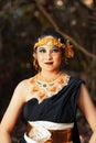 Javanese woman with golden crown and black costume chilling inside the forest while wearing makeup