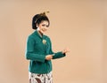 javanese woman in green kebaya standing and pointing with her thumbs