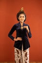 javanese woman in navy kebaya standing with smile while touch her kebaya