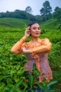 a Javanese woman on vacation in a tea garden wearing a yellow dress