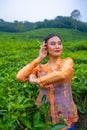 a Javanese woman on vacation in a tea garden wearing a yellow dress