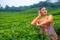 a Javanese woman on vacation in a tea garden wearing a yellow dress